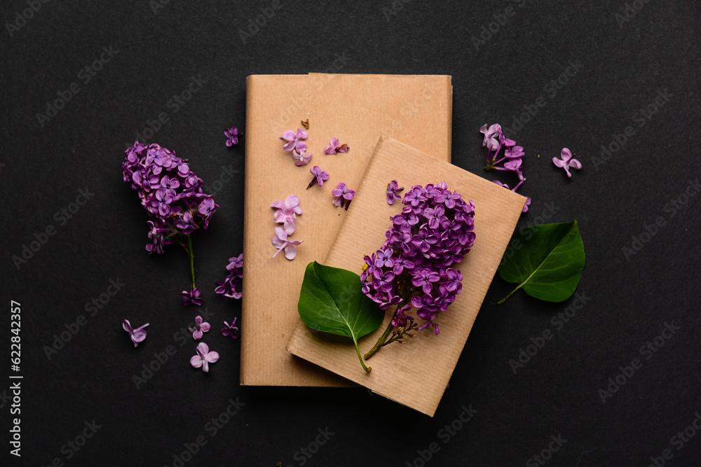 Beautiful lilac flowers and books on dark background