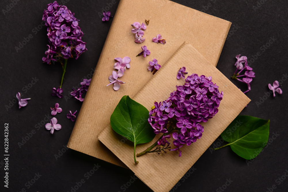 Beautiful lilac flowers and books on dark background