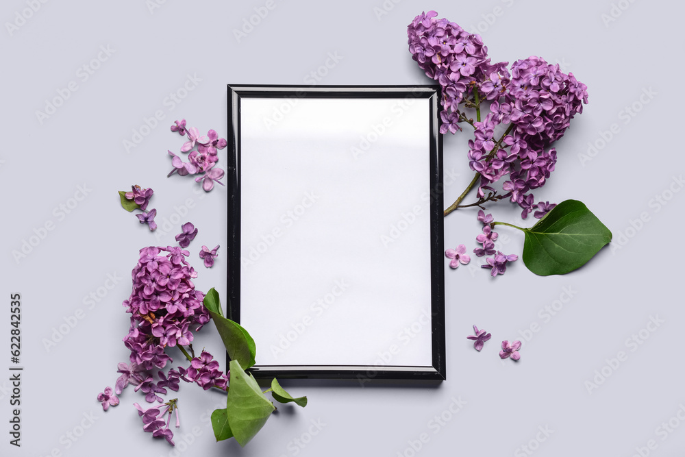 Composition with beautiful lilac flowers and blank frame on light background