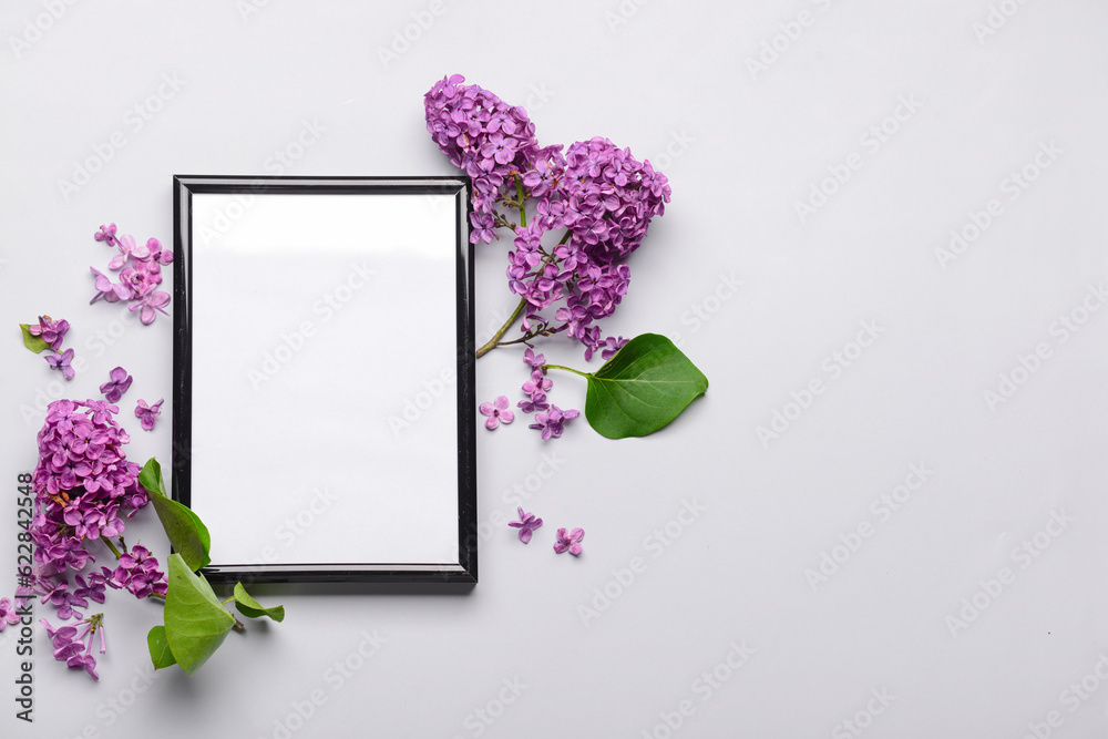 Composition with beautiful lilac flowers and blank frame on light background