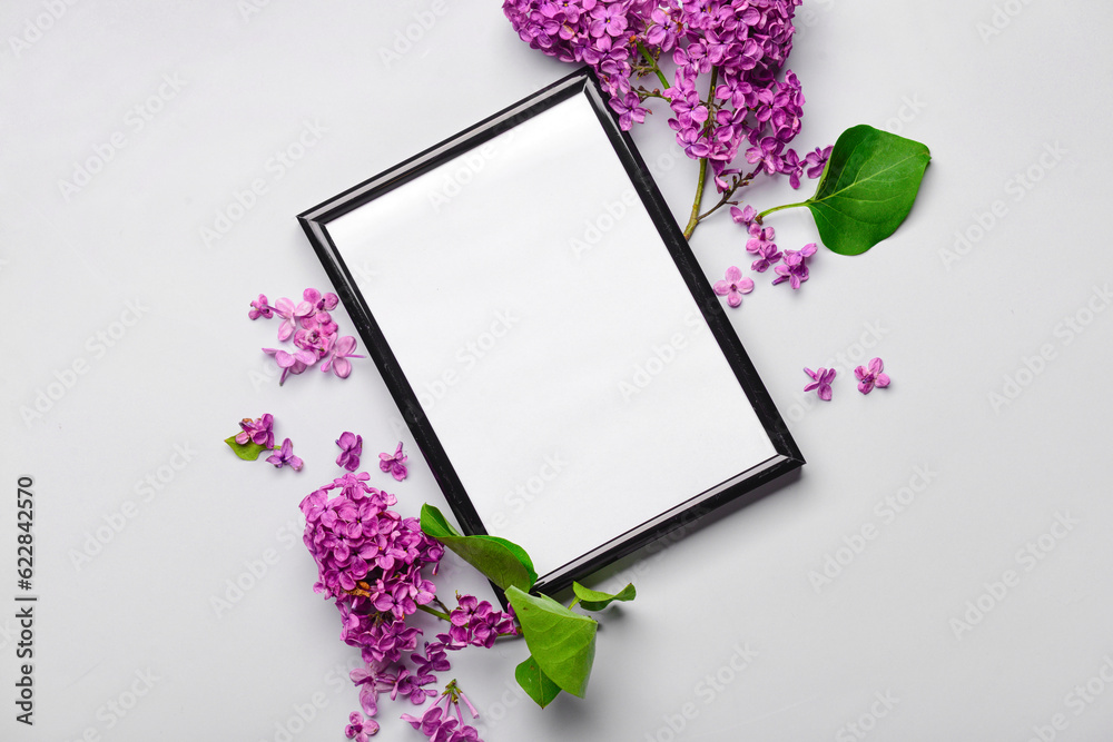 Composition with beautiful lilac flowers and blank frame on light background