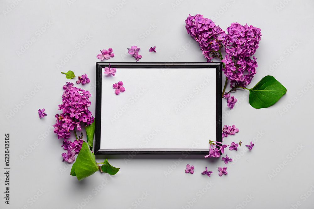 Composition with beautiful lilac flowers and blank frame on light background