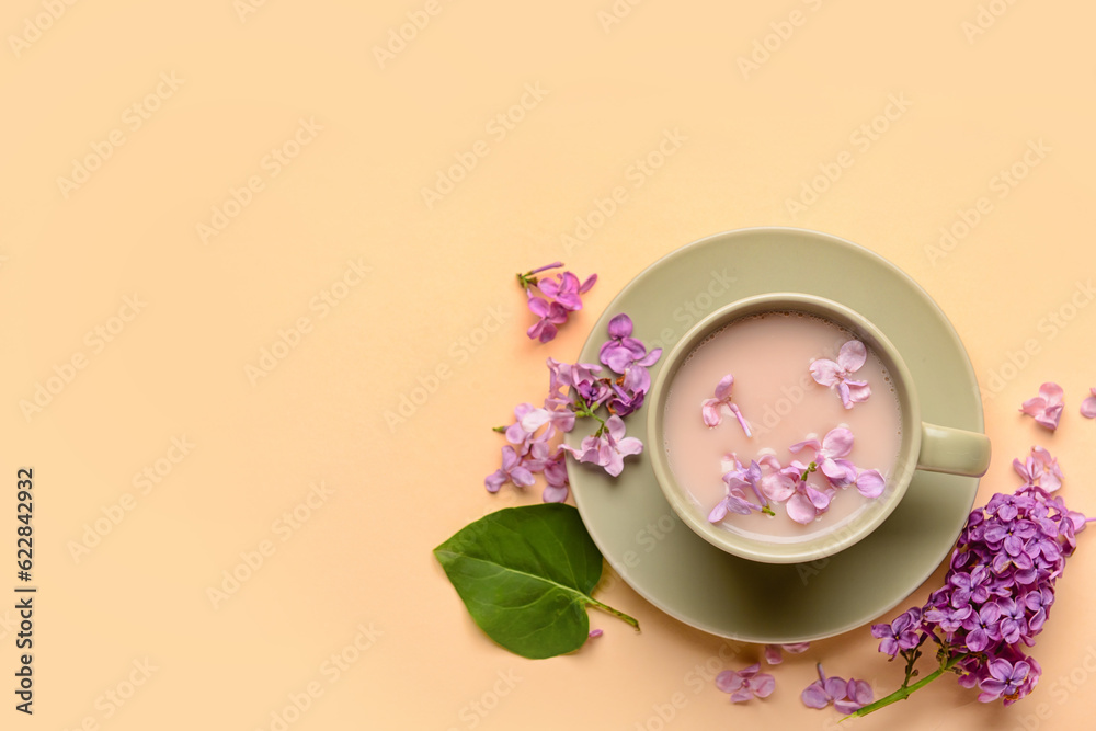 Cup of coffee and beautiful lilac flowers on beige background