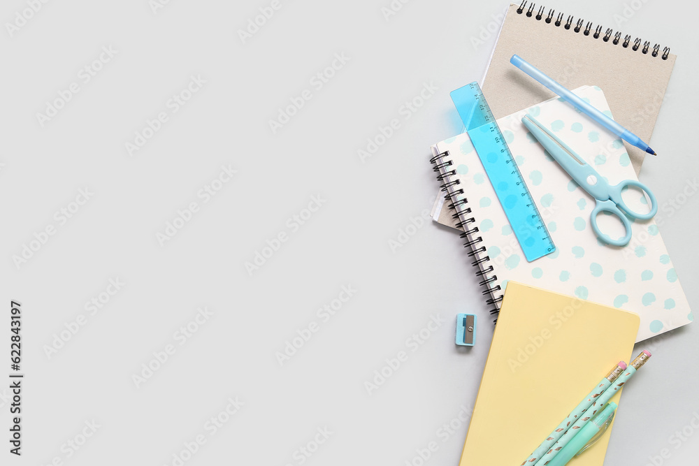 Notebooks and school stationery on grey background