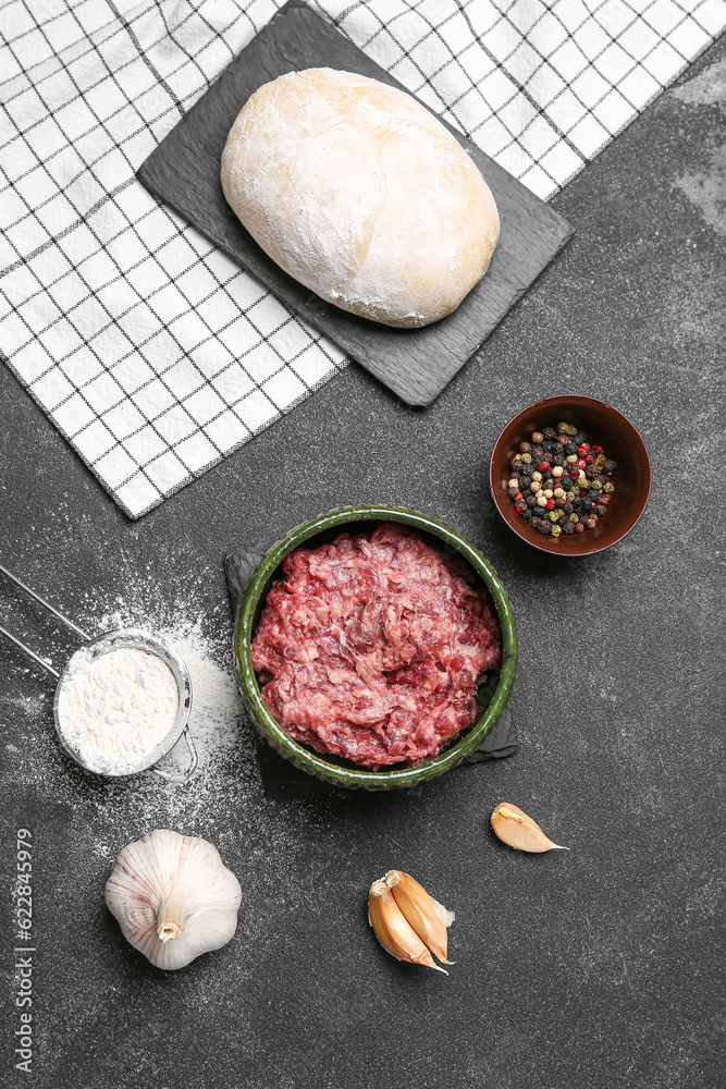 Raw dough and ingredients for preparing dumplings on black background