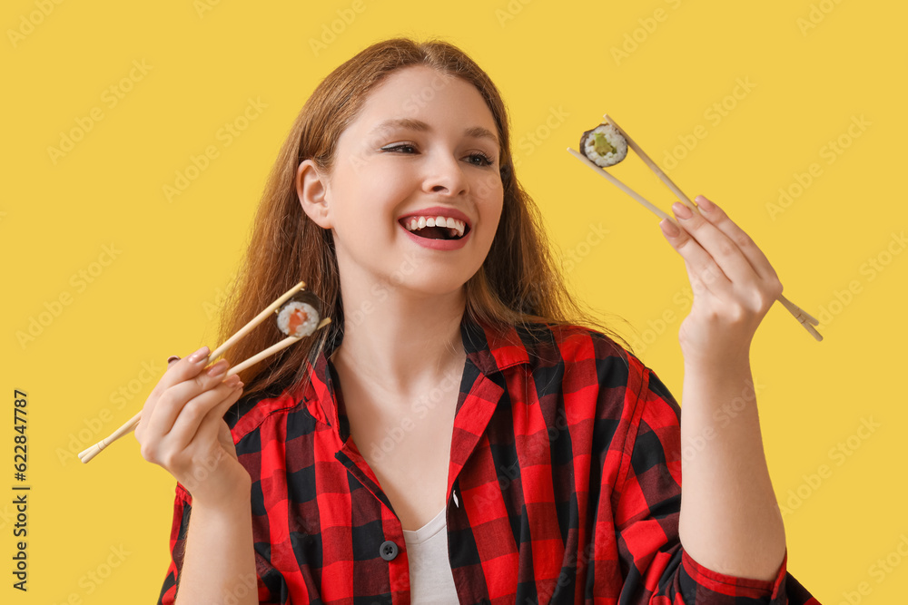 Young woman with tasty sushi rolls on yellow background, closeup