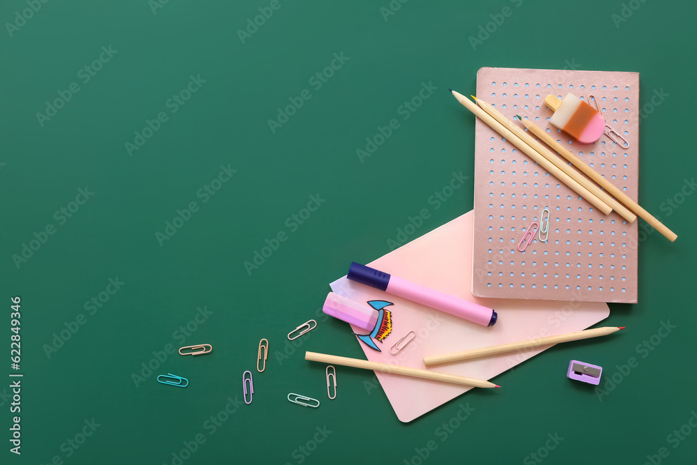 Creative composition with paper rocket and different stationery on green chalkboard