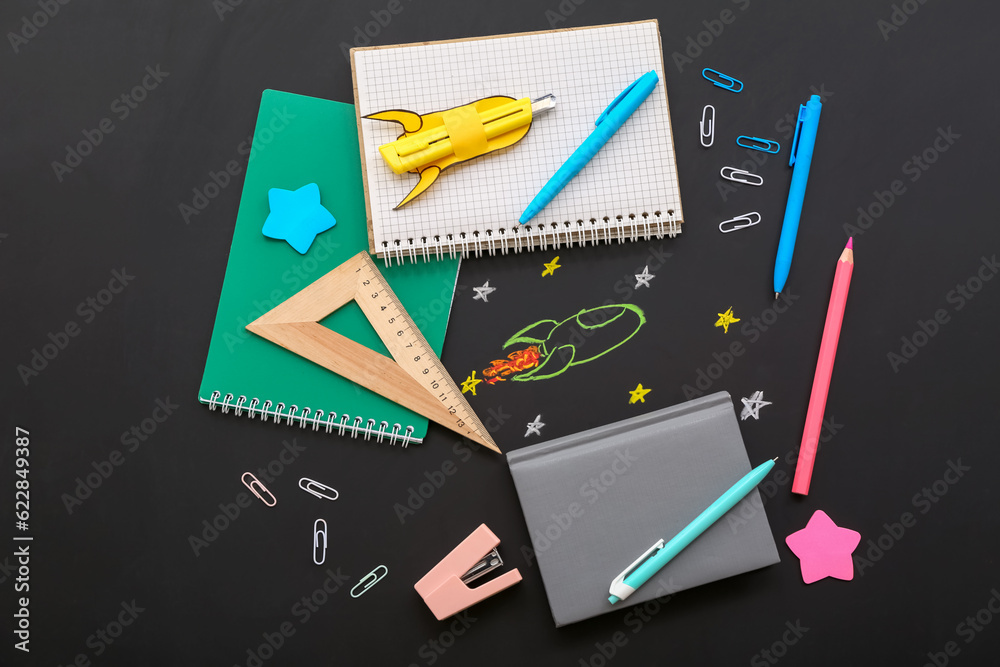 Creative composition with rockets and different stationery on black chalkboard