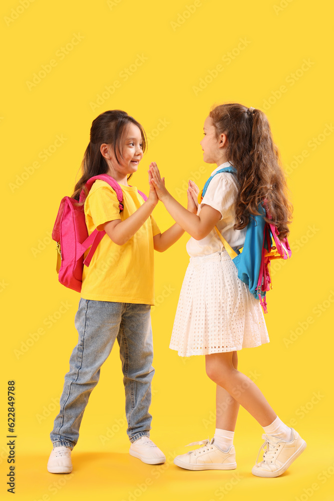 Little schoolgirls on yellow background