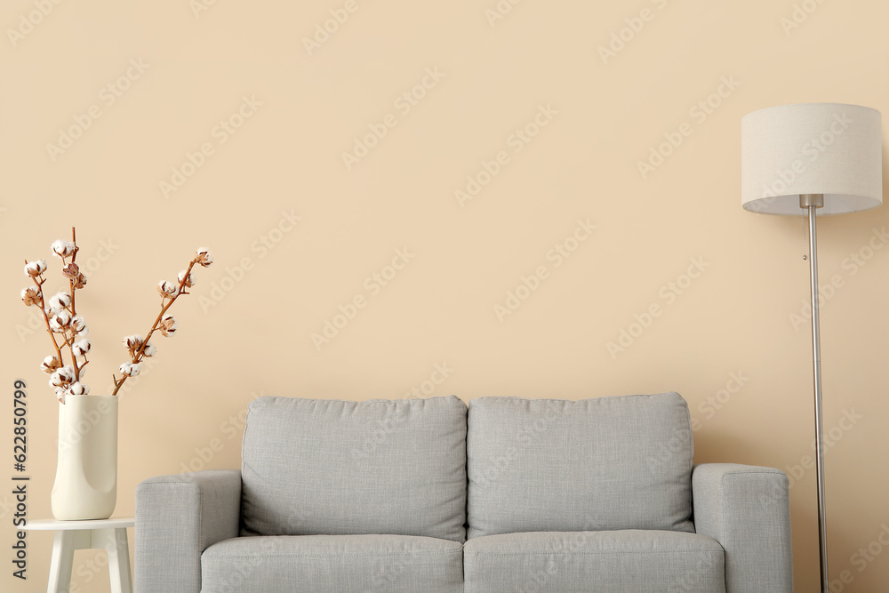 Interior of living room with sofa, lamp and cotton branches