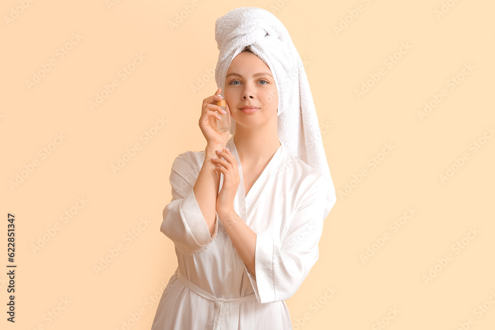 Pretty young woman with cosmetic oil on beige background