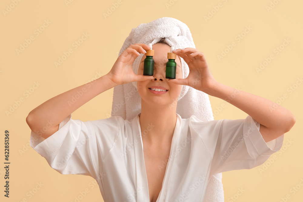 Funny young woman with cosmetic oil on beige background