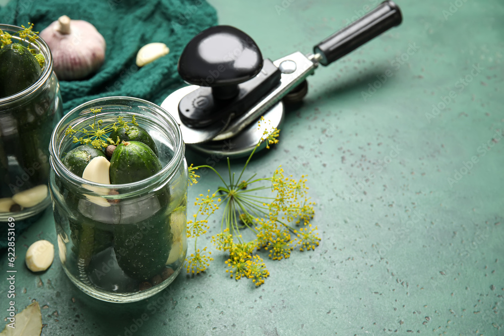 Jars with fresh cucumbers for preservation on green background