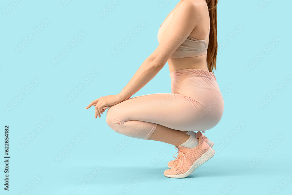 Young woman in sportswear on light blue background