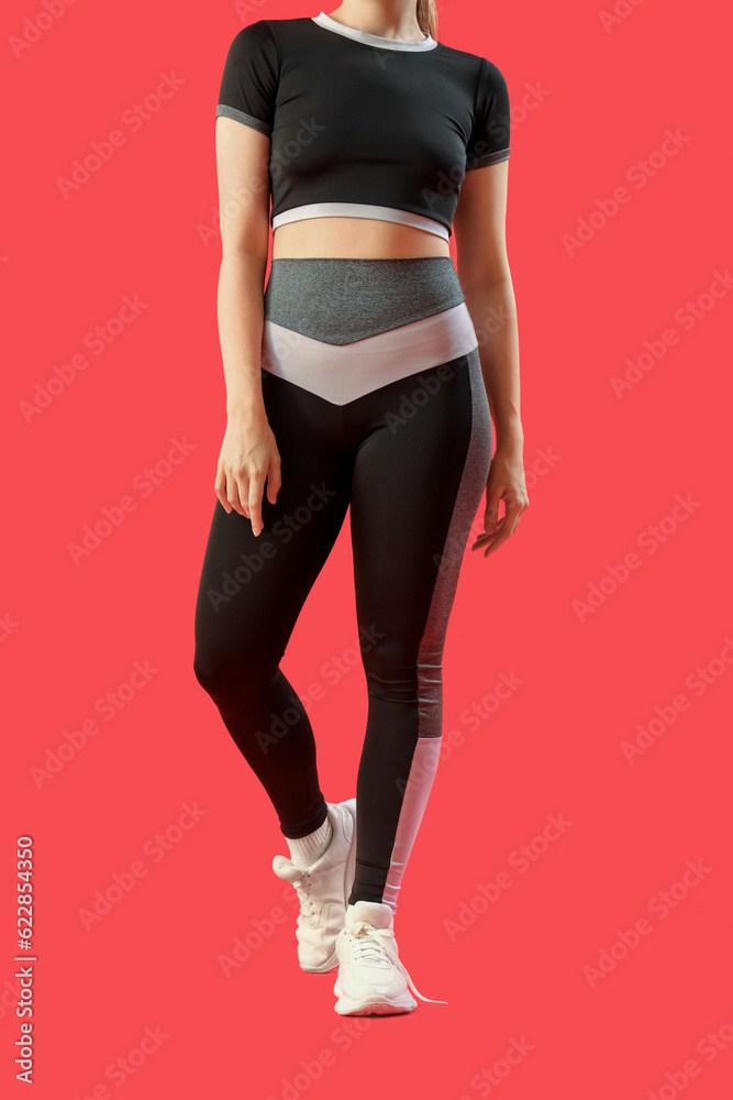 Young woman in sportswear on red background