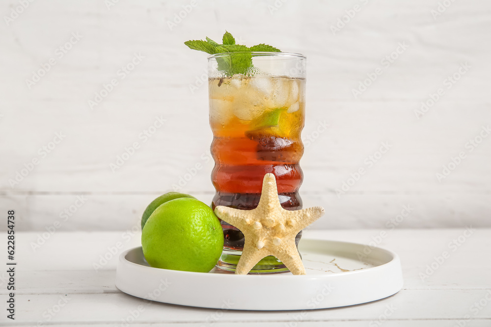 Plate with glass of cold Cuba Libre cocktail and starfish on white wooden background