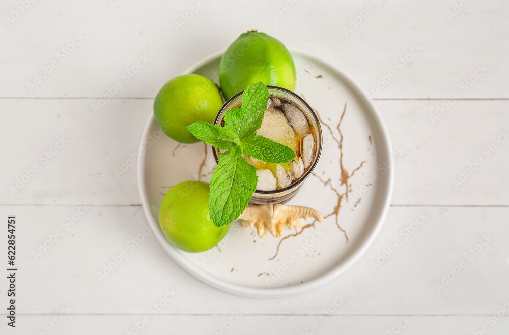 Plate with glass of cold Cuba Libre cocktail and starfish on white wooden background