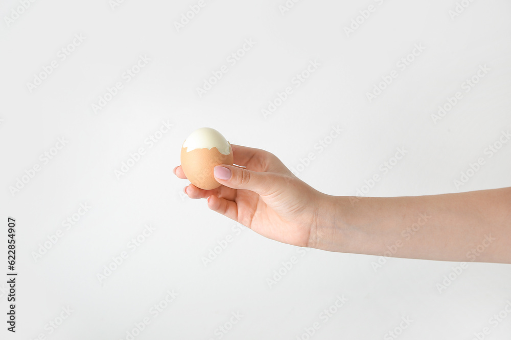 Female hand holding boiled chicken egg on white background