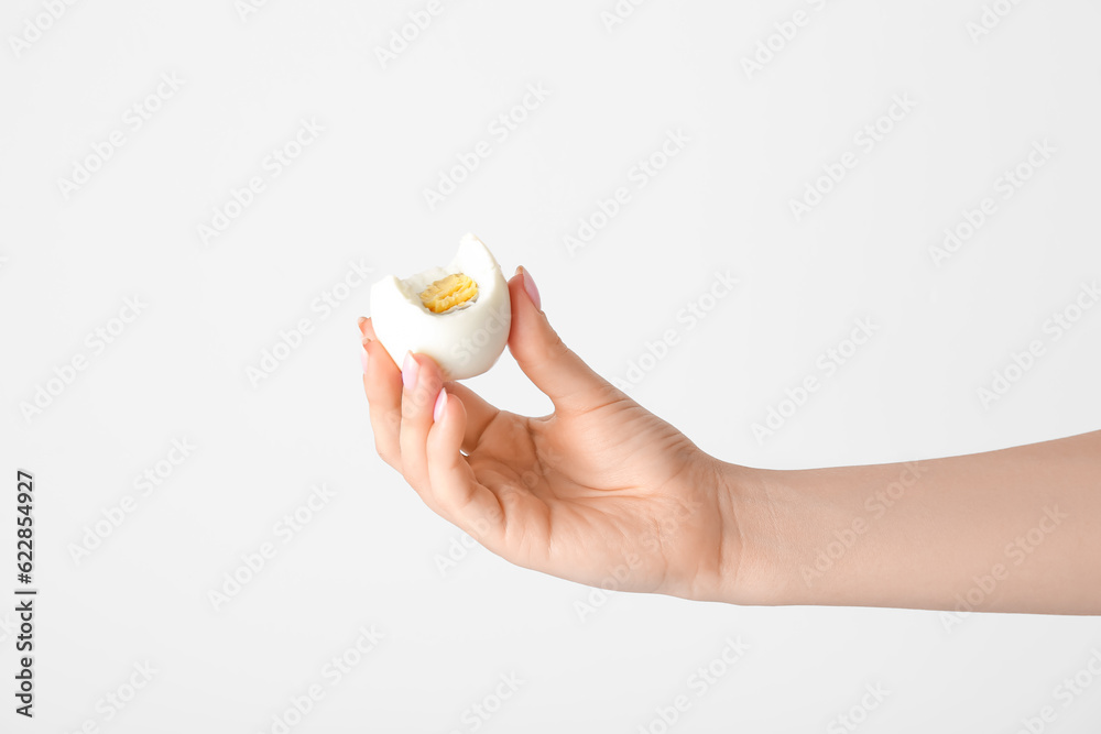 Female hand holding boiled chicken egg on white background