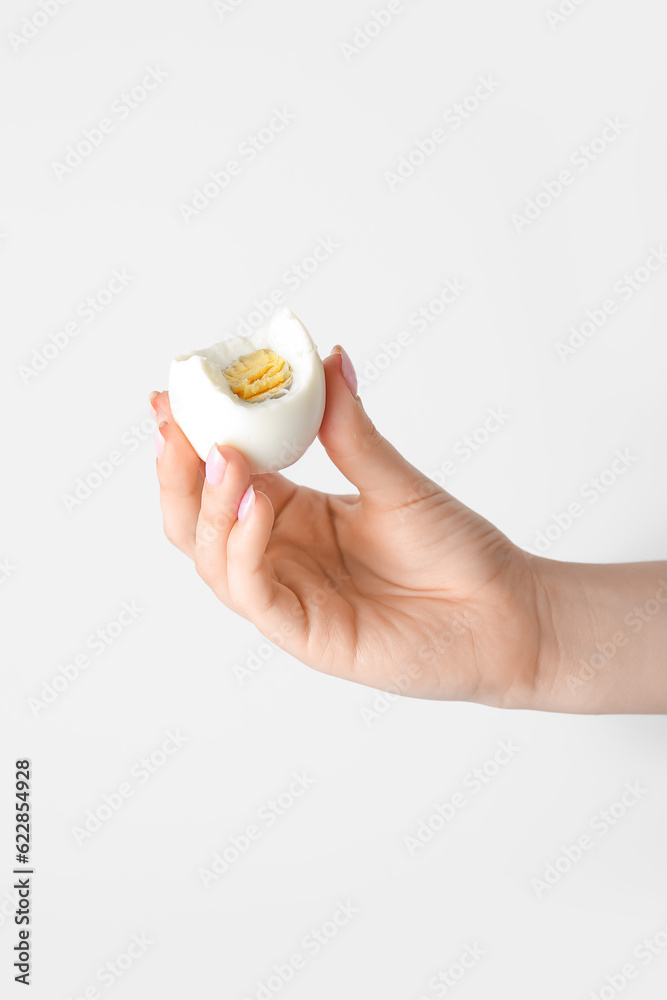 Female hand holding boiled chicken egg on white background