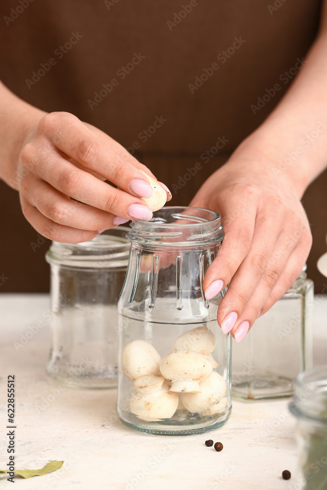 Woman preparing mushrooms for canning at table