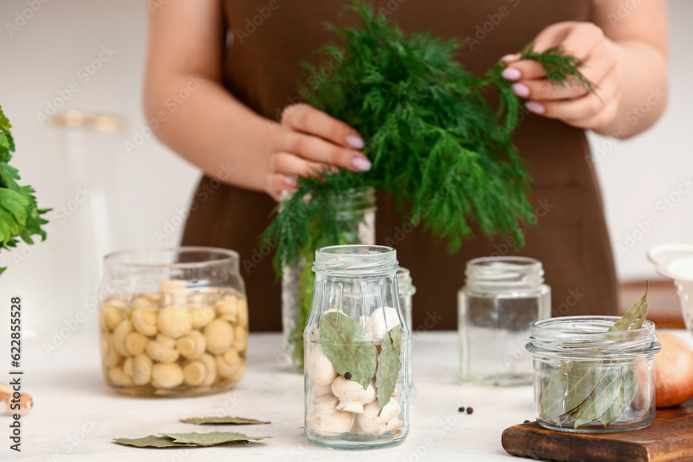 Woman preparing mushrooms for canning at table in kitchen