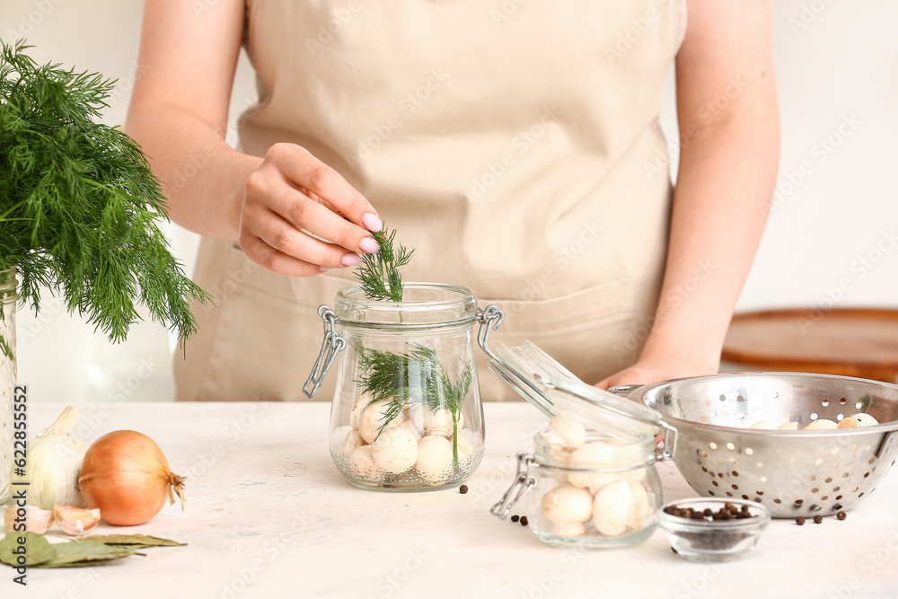 Woman preparing mushrooms for canning at table in kitchen