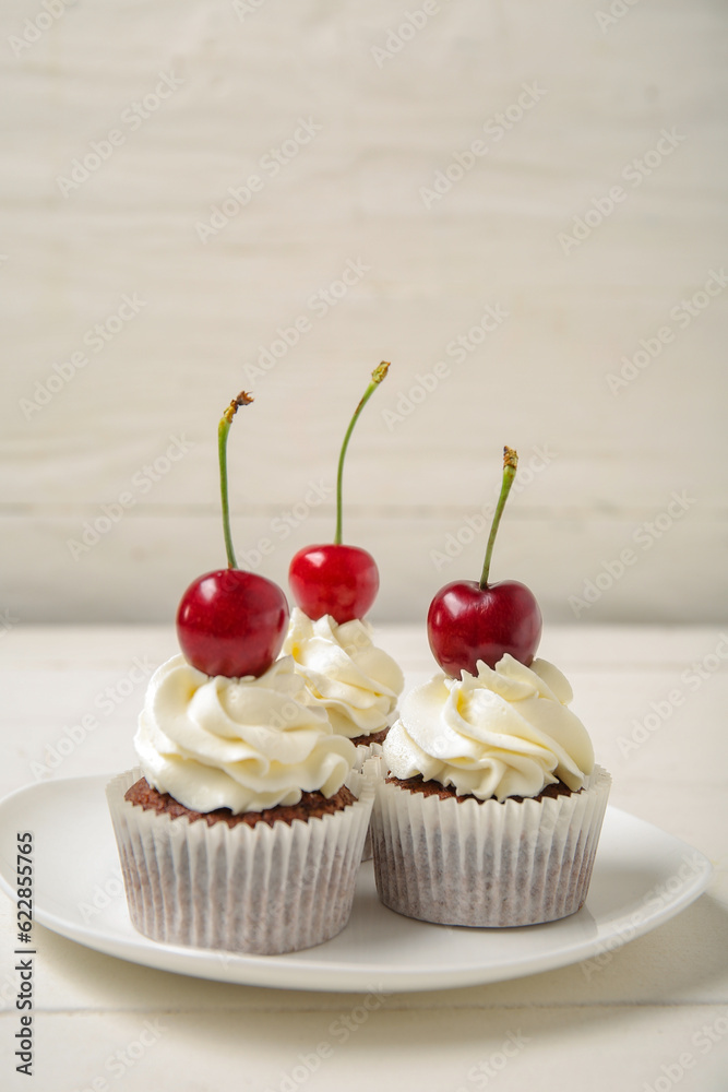 Plate with tasty cherry cupcakes on table