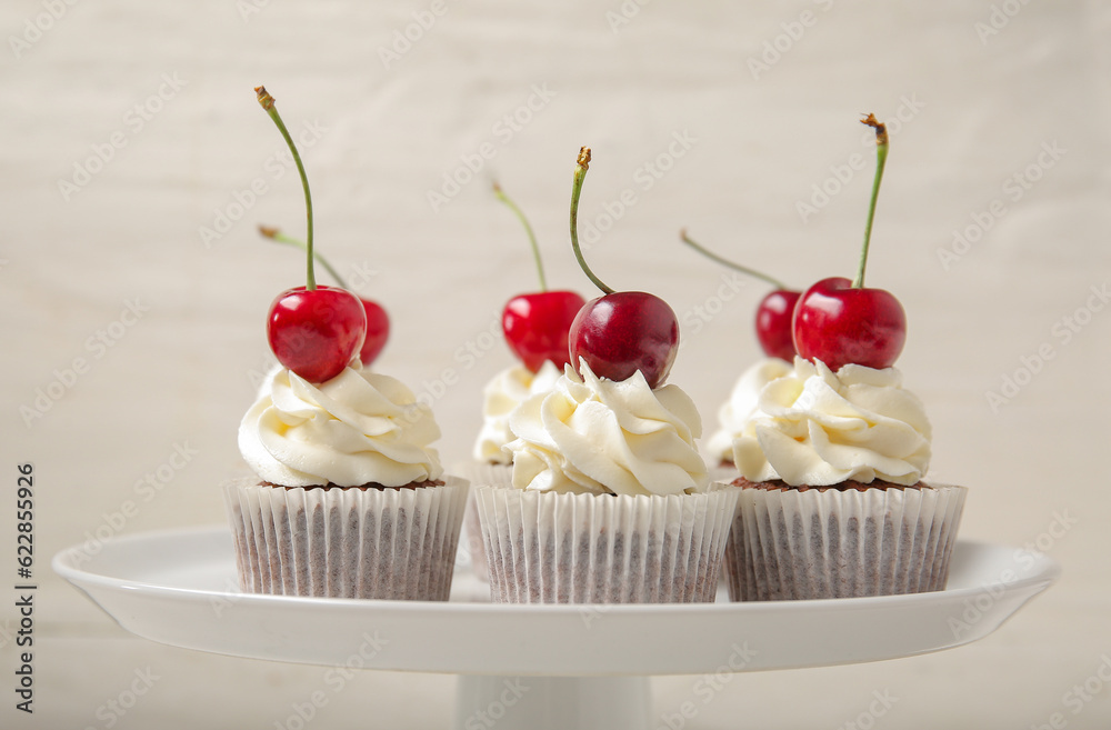 Stand with tasty cherry cupcakes on light background