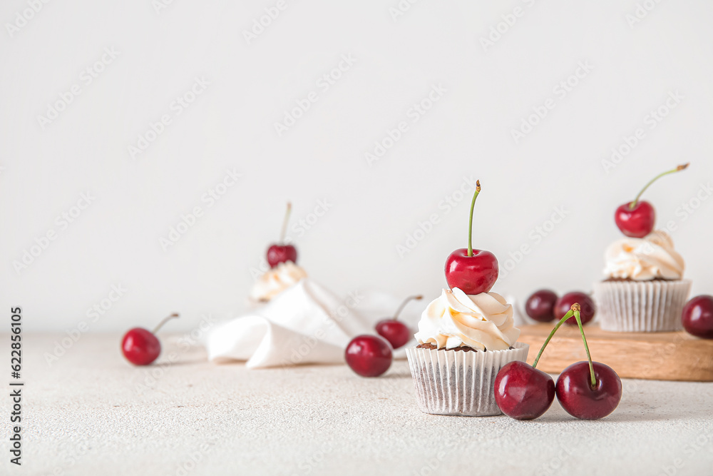 Tasty cherry cupcake on light background