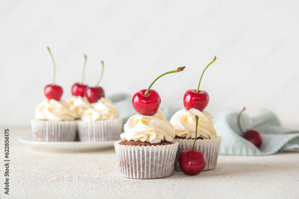 Tasty cherry cupcakes on light background