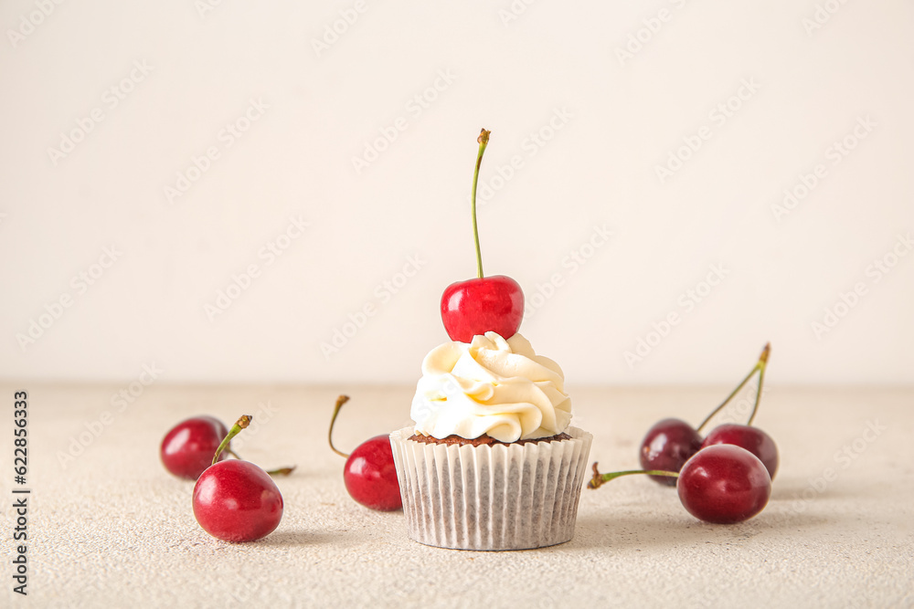 Tasty cherry cupcake on light background