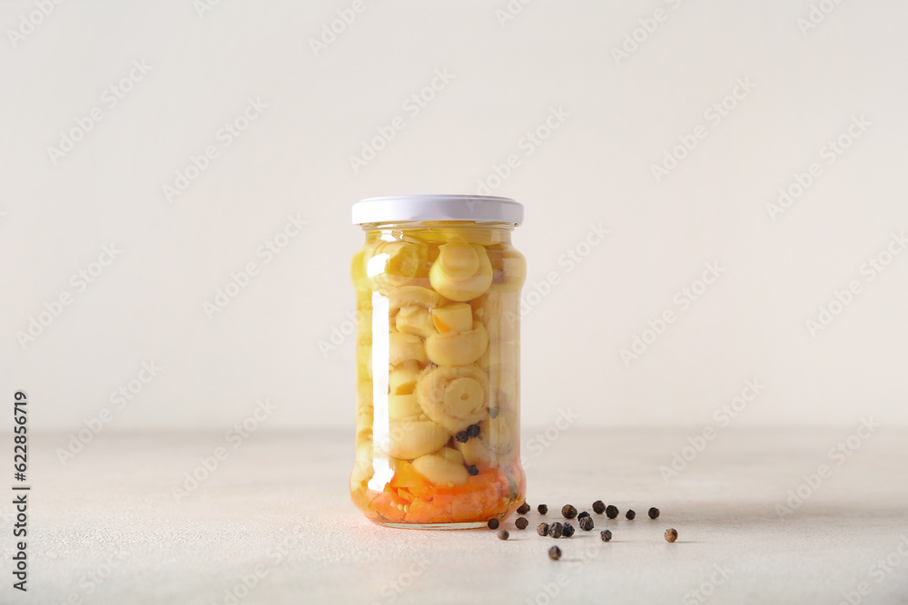 Jar with canned mushrooms on light background