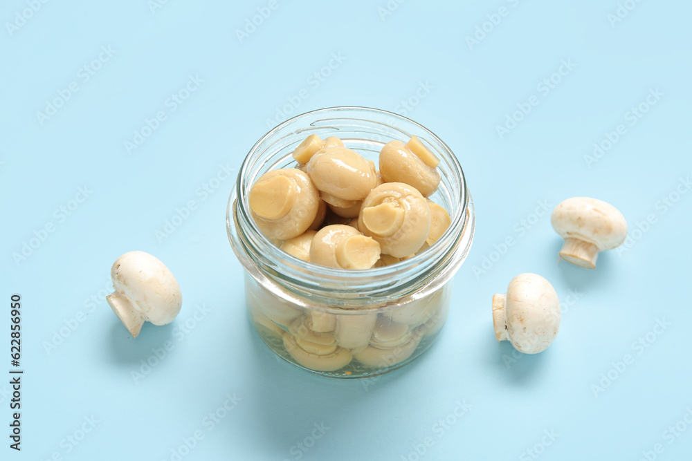 Jar with canned mushrooms on blue background