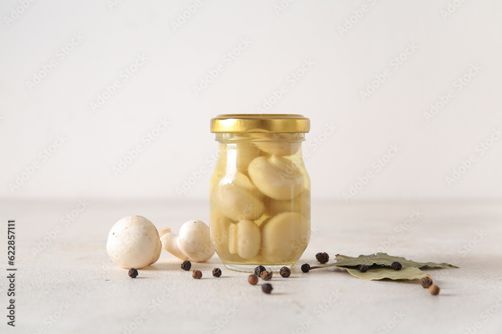 Jar with canned mushrooms on light background