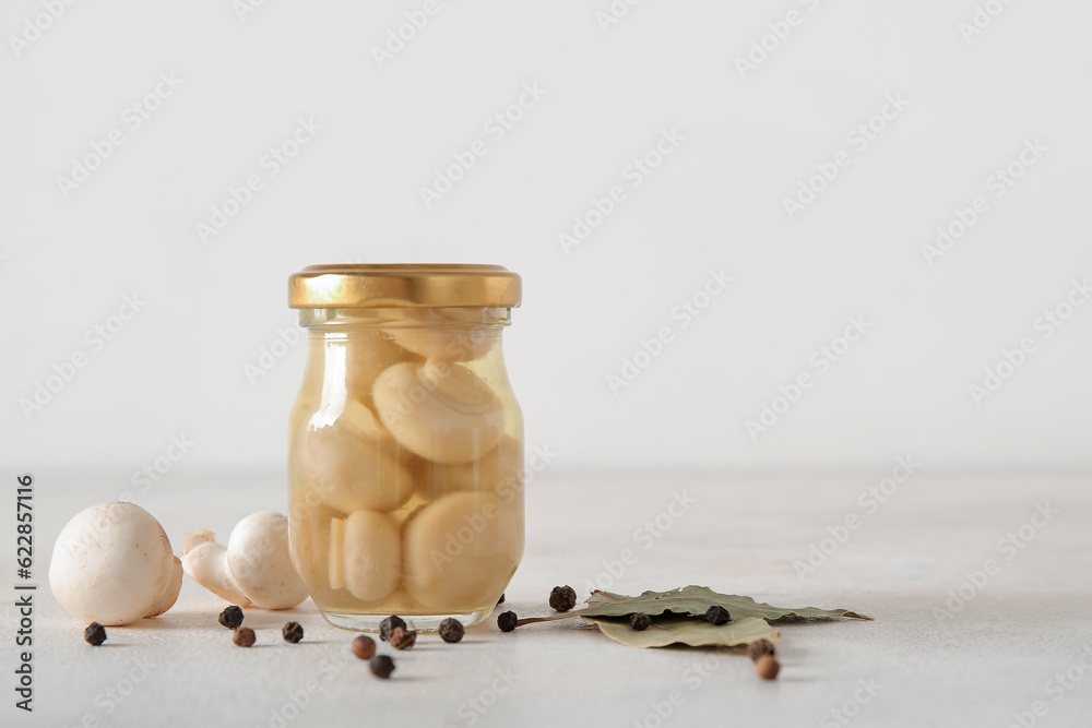 Jar with canned mushrooms on light background