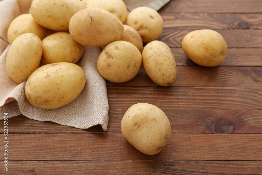 Many raw potatoes on wooden background