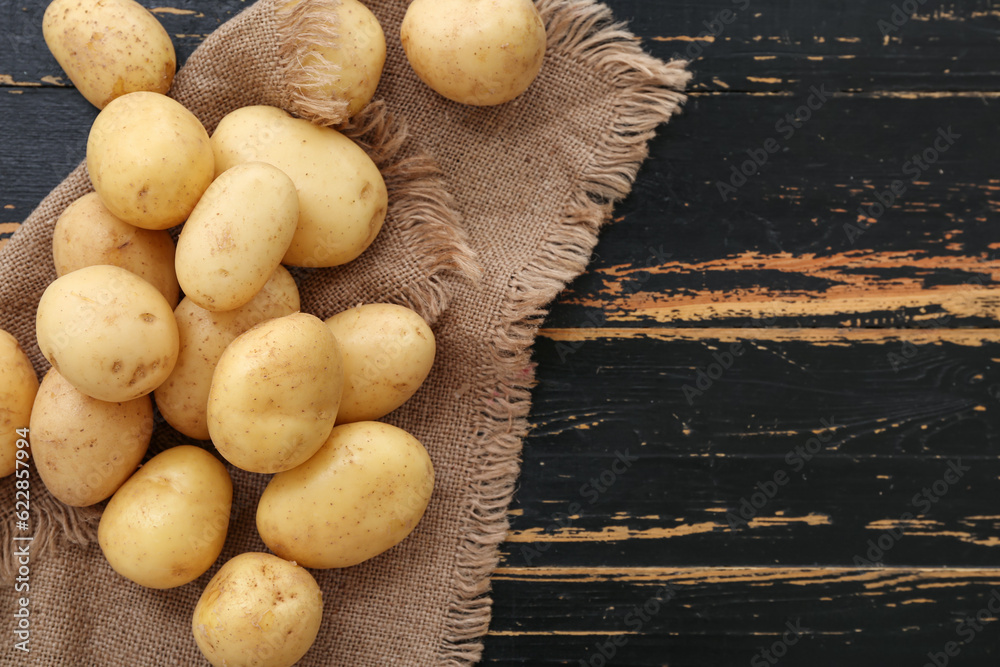 Many raw potatoes on black wooden background