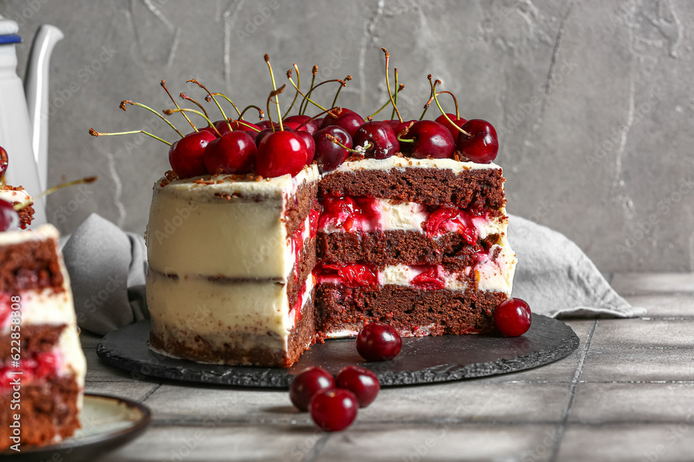 Board with tasty cherry cake on grey tile table