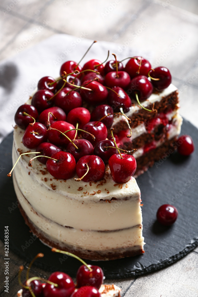 Board with tasty cherry cake on grey tile table