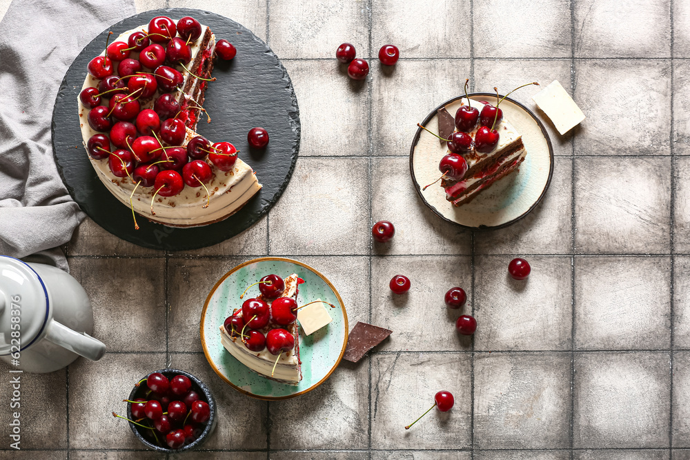 Tasty cherry cake and plates with pieces on grey tile table