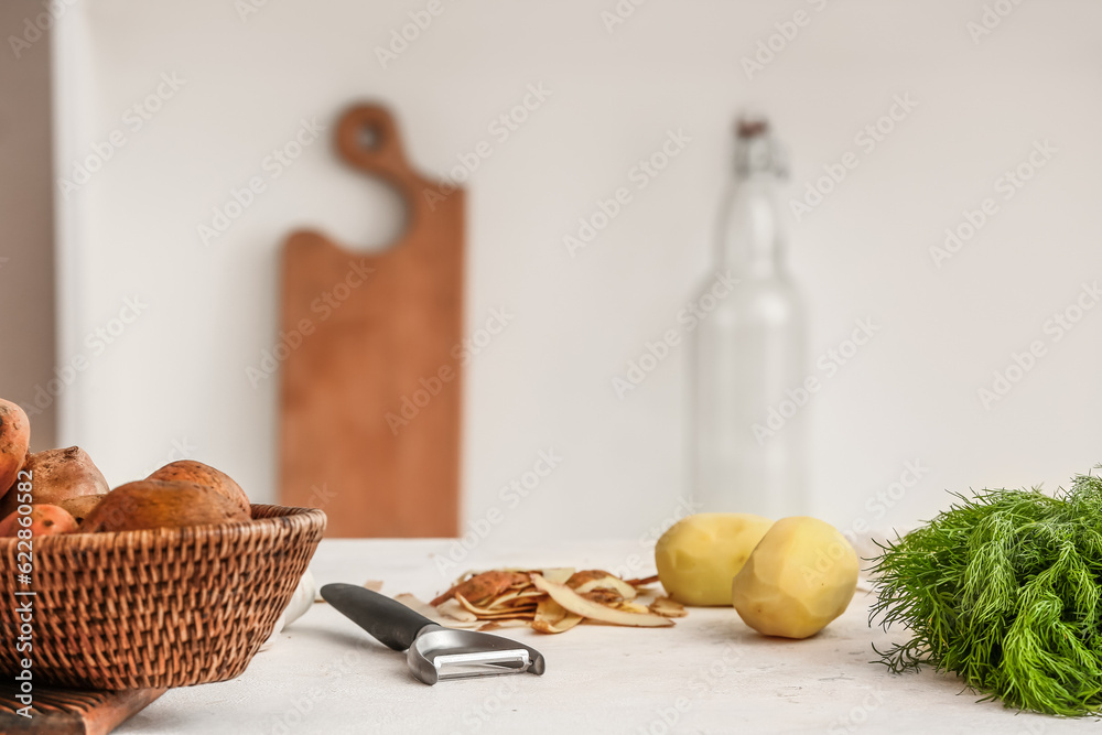 Peeled raw potatoes on table in kitchen