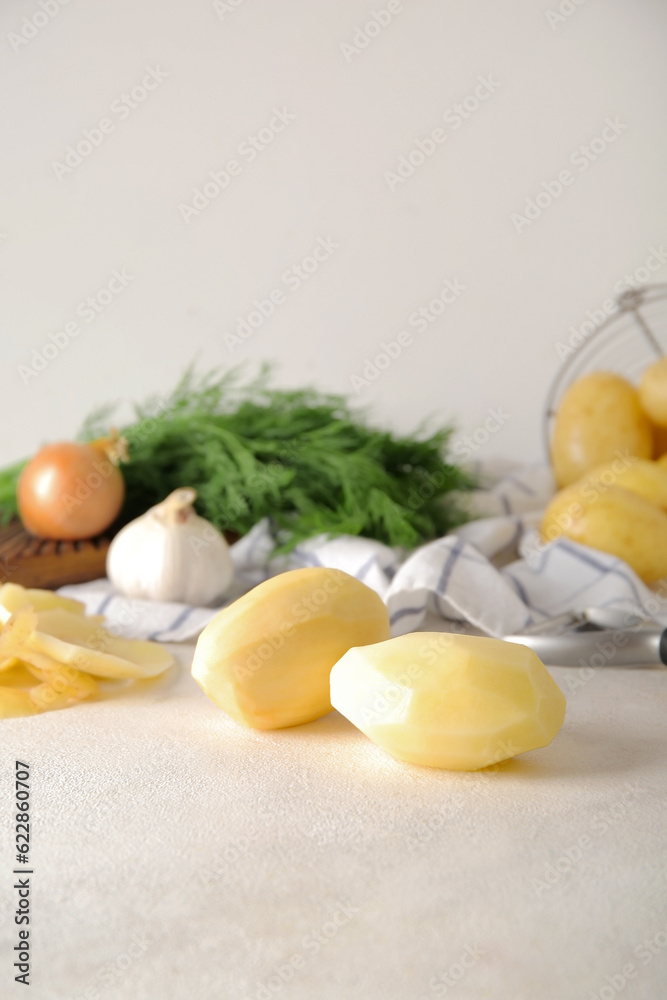 Peeled potatoes on light background