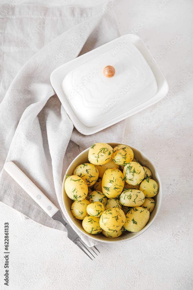 Bowl with boiled baby potatoes on light background