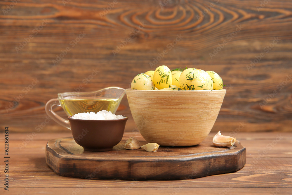 Bowl with boiled baby potatoes on wooden background