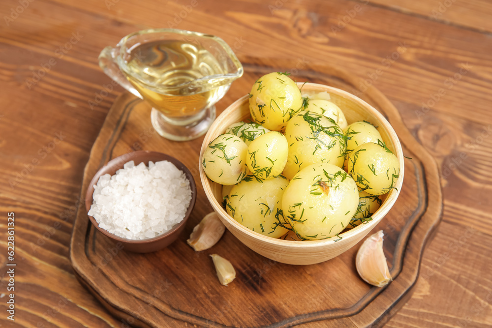 Bowl with boiled baby potatoes on wooden background