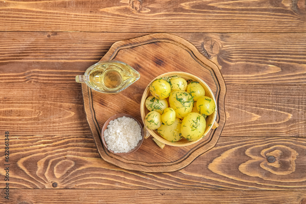 Bowl with boiled baby potatoes on wooden background