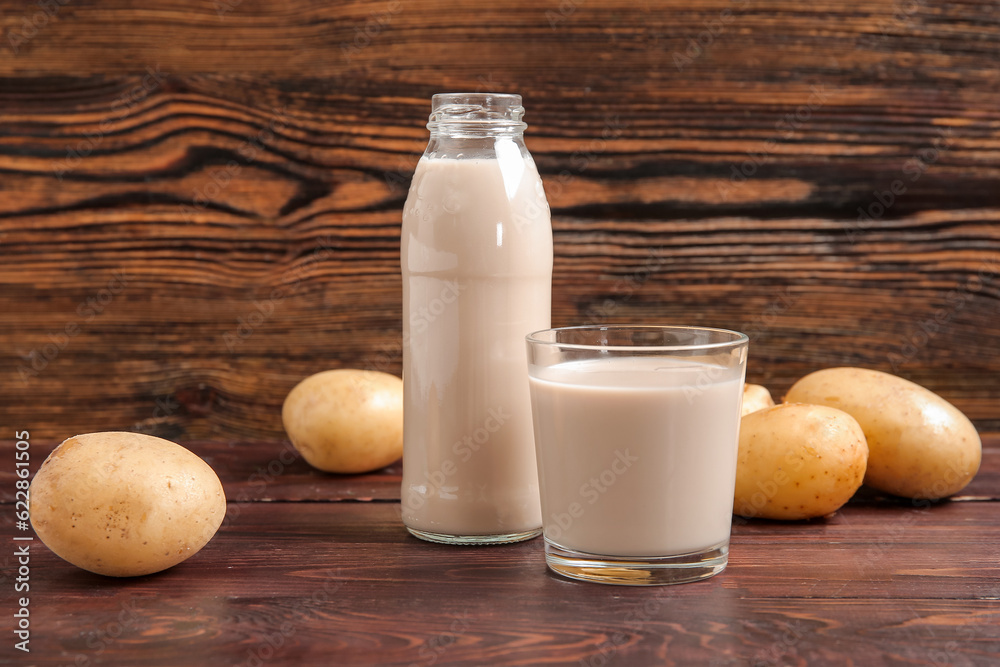 Bottle and glass of tasty potato milk on wooden background