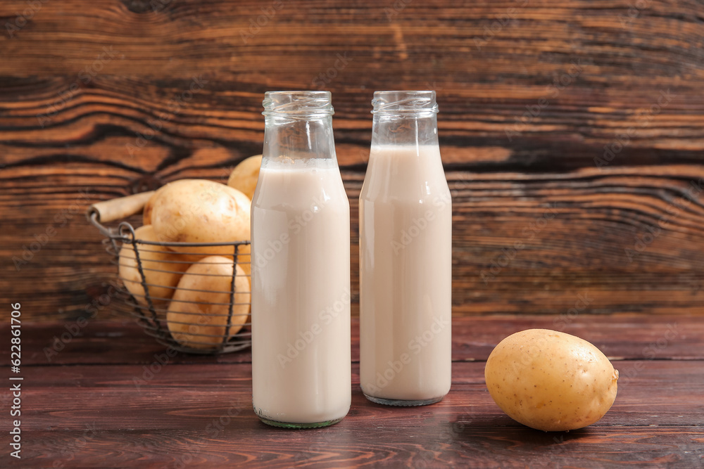 Bottles of tasty potato milk on wooden background