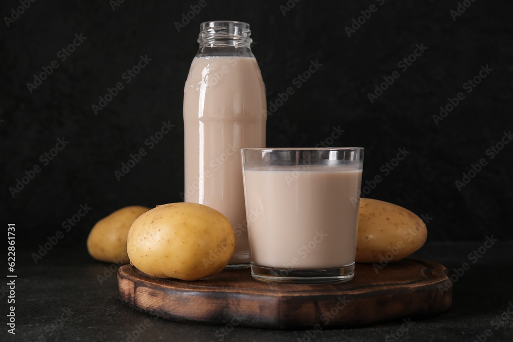 Bottle and glass of tasty potato milk on black background